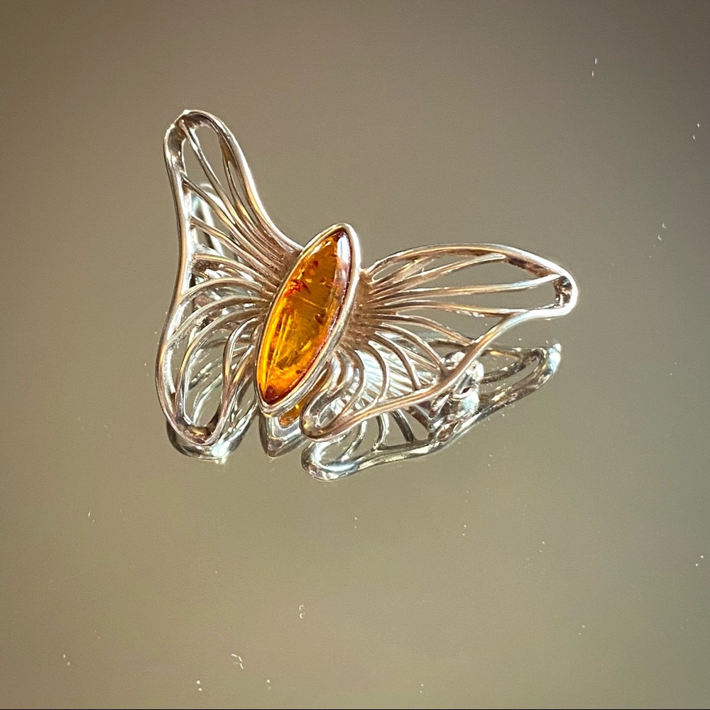 amber stone,  set in a sterling silver butterfly pin, with secured clasp.